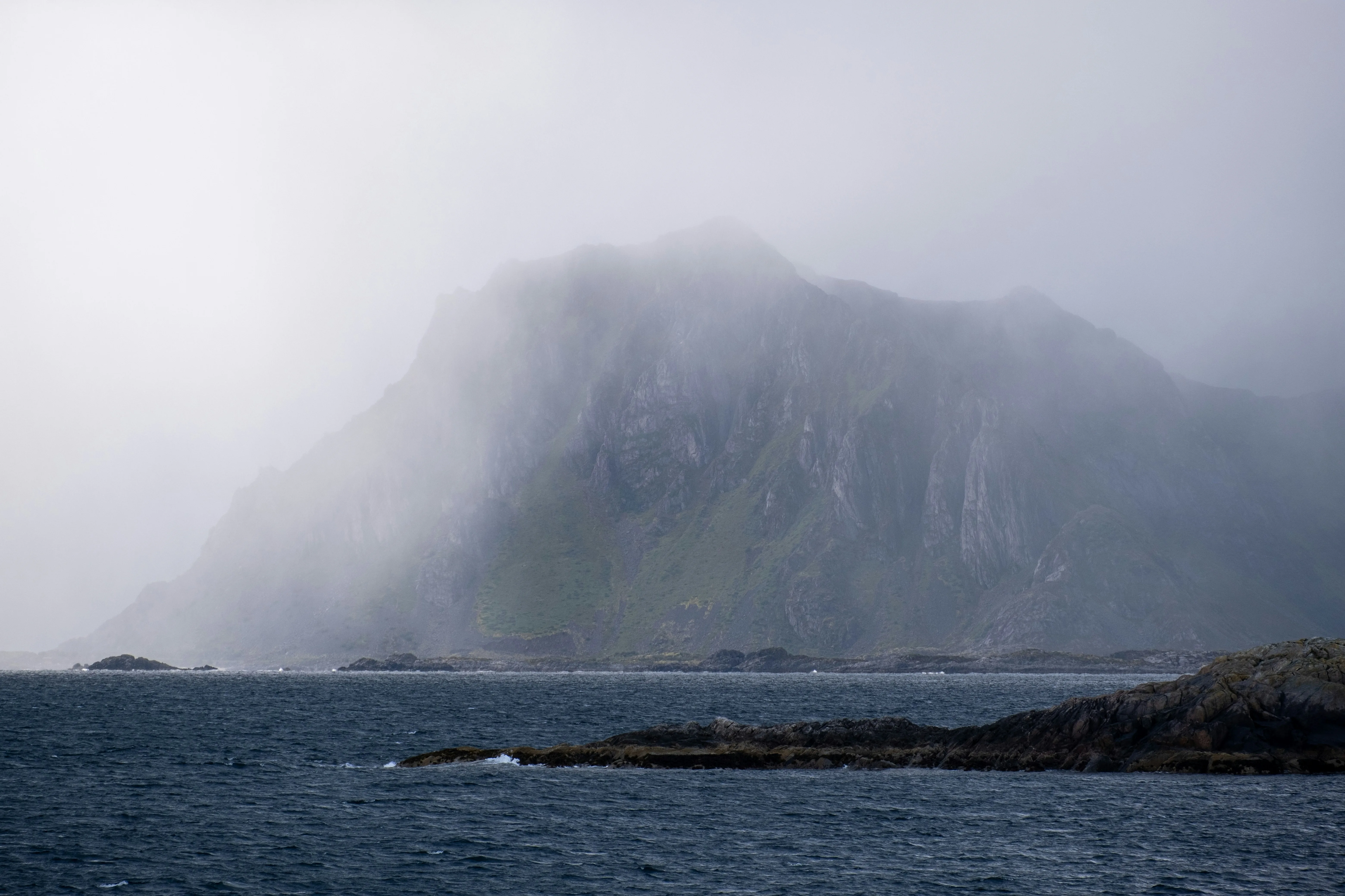 Fog-shrouded coastal mountains rising from the sea on Norway's Atlantic coast