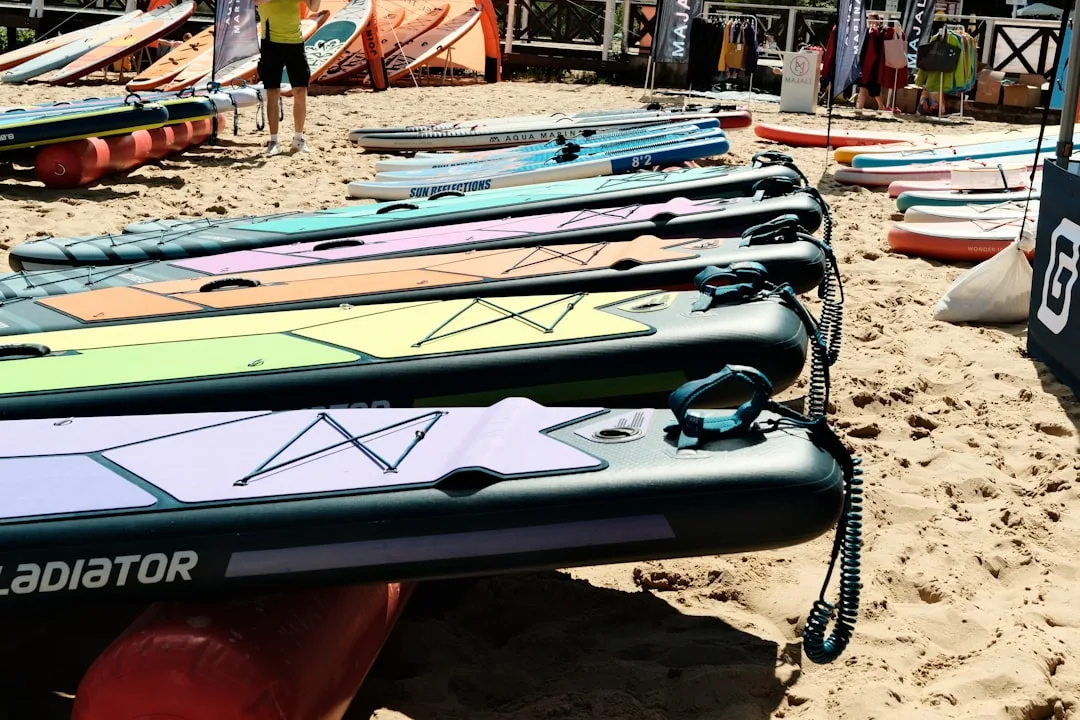 Bunte aufblasbare SUP-Boards in einer Reihe auf einem Sandstrand vor dem Meer