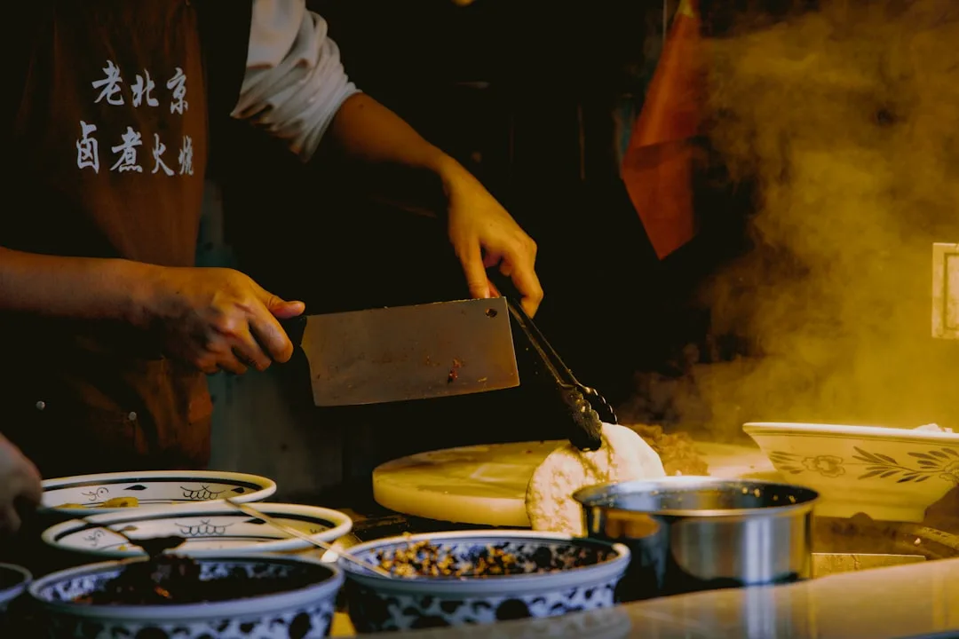 Local chef working with cleaver and tongs cooking in an Asian kitchen