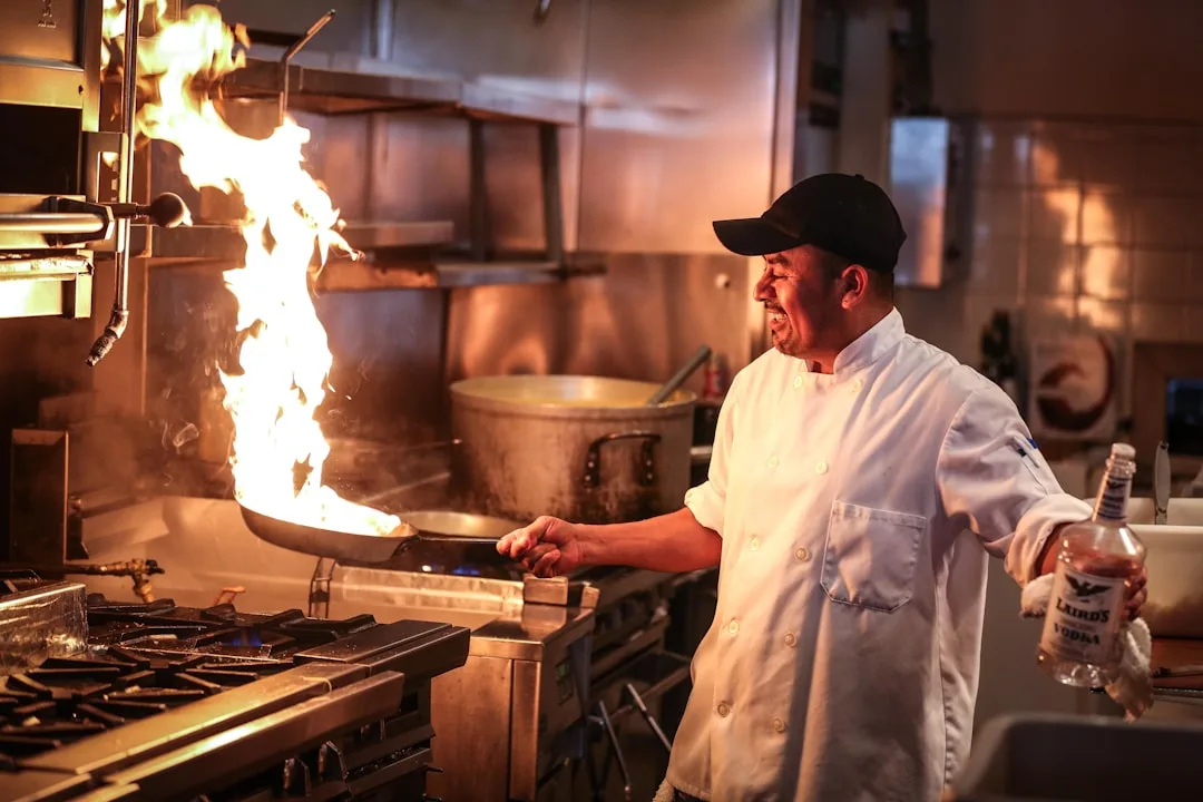 Star chef in white uniform cooking with a flame in restaurant kitchen