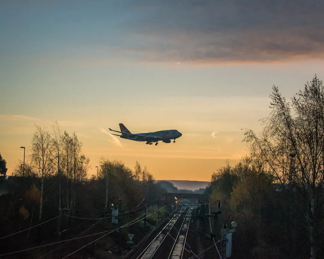 Airplane landing at sunset over railway tracks – comparing carbon footprint of flying versus train travel