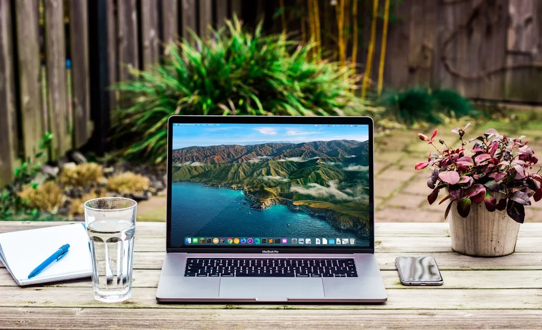 MacBook on a garden terrace with plants and a glass of water