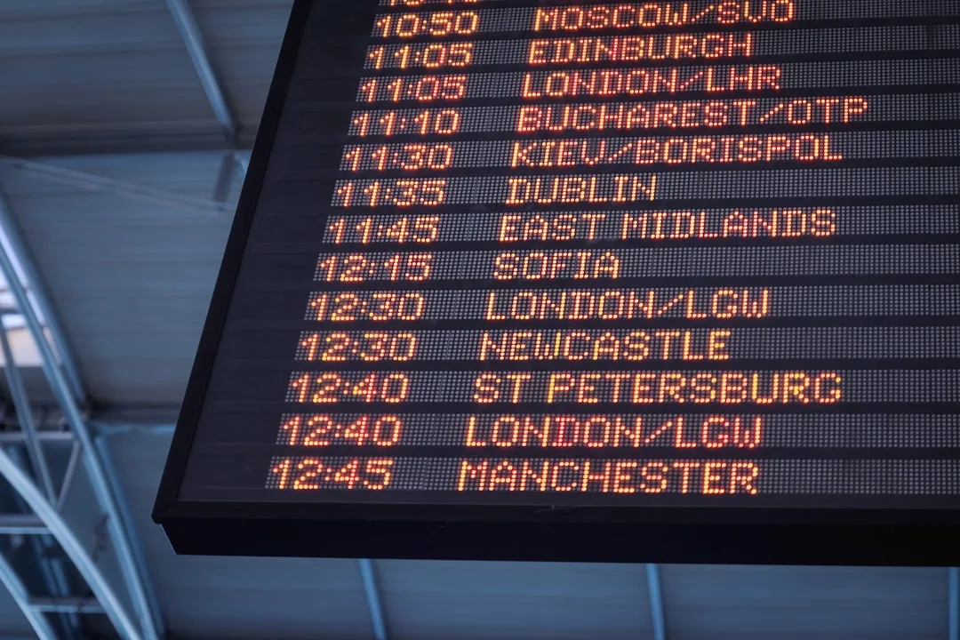 Black airport departure board with yellow destination cities and departure times