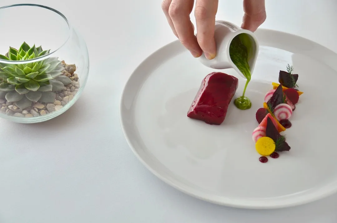 Chef placing a green herb garnish on an elegant fine dining plate