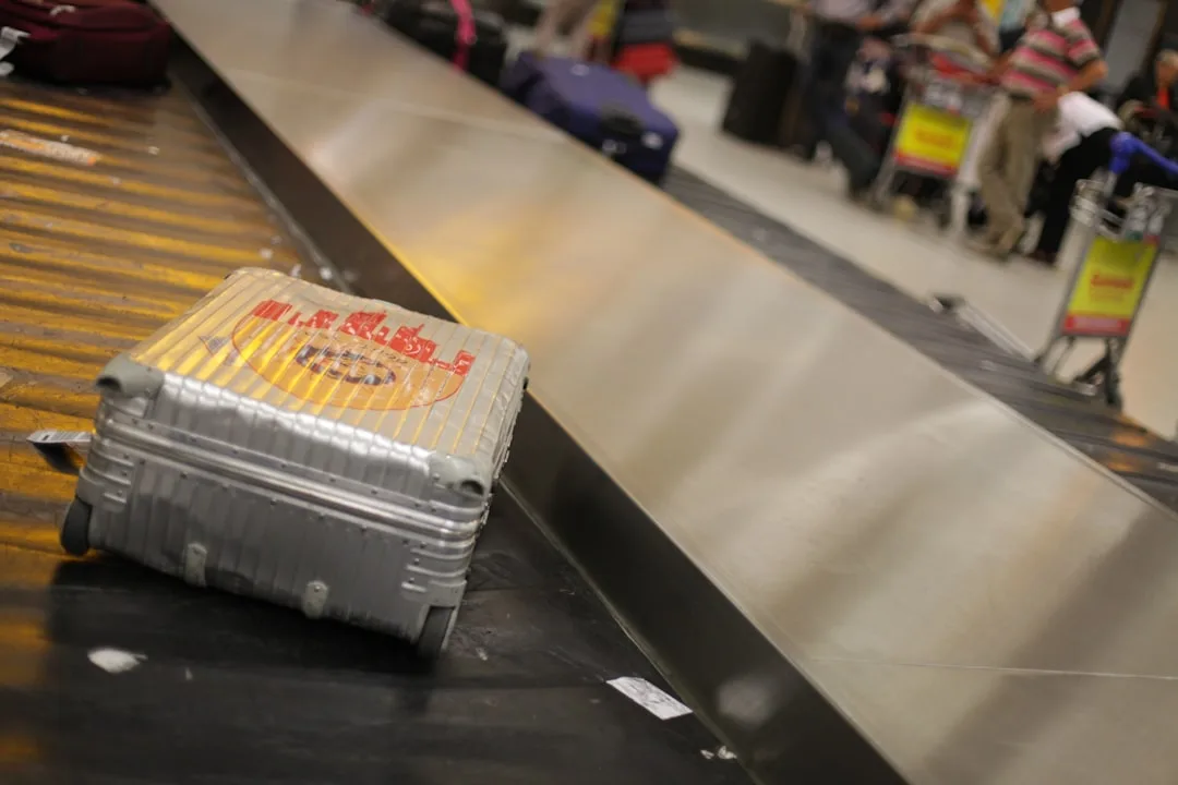 Grauer Hartschalenkoffer mit Prioritäts-Tag auf dem Gepäckband am Flughafen