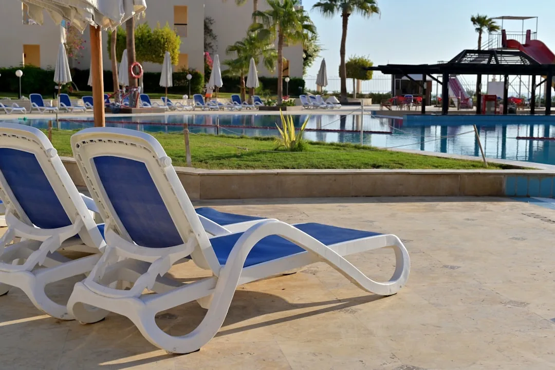 Blue sun loungers at a hotel pool with white umbrellas on a sunny holiday day