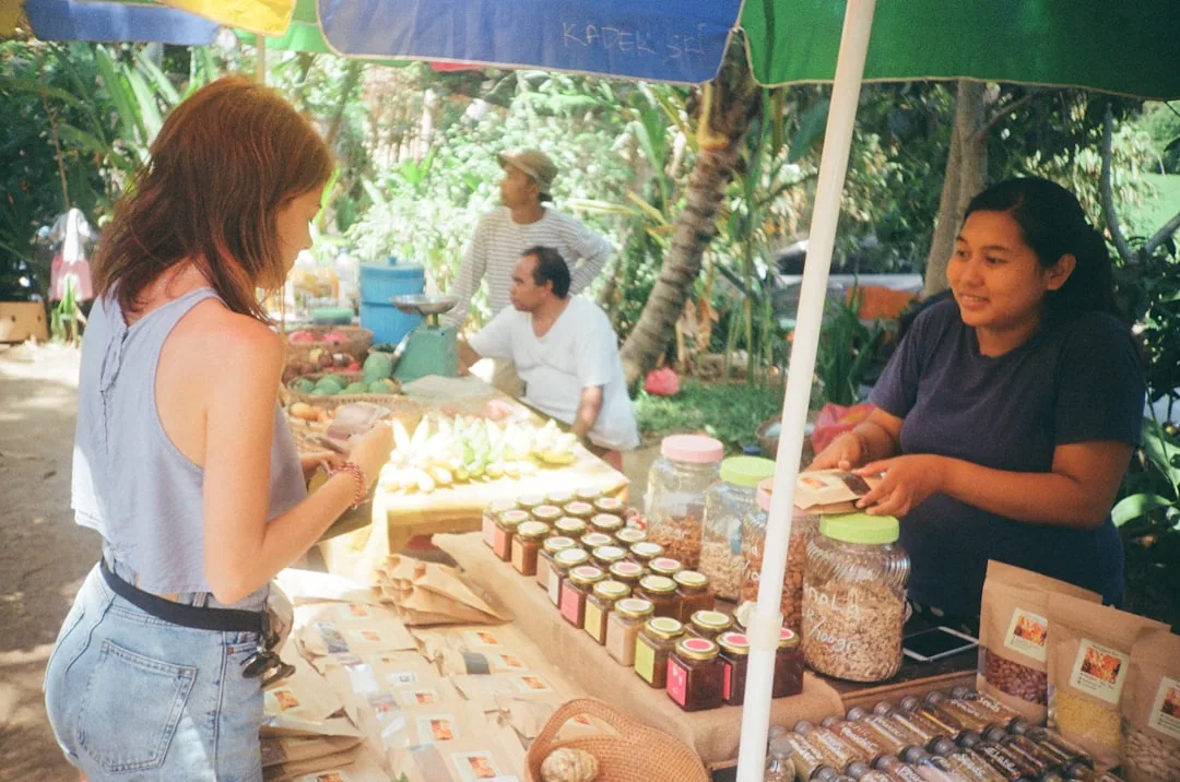 Traveler buying from a local market vendor at a colorful tropical market stall