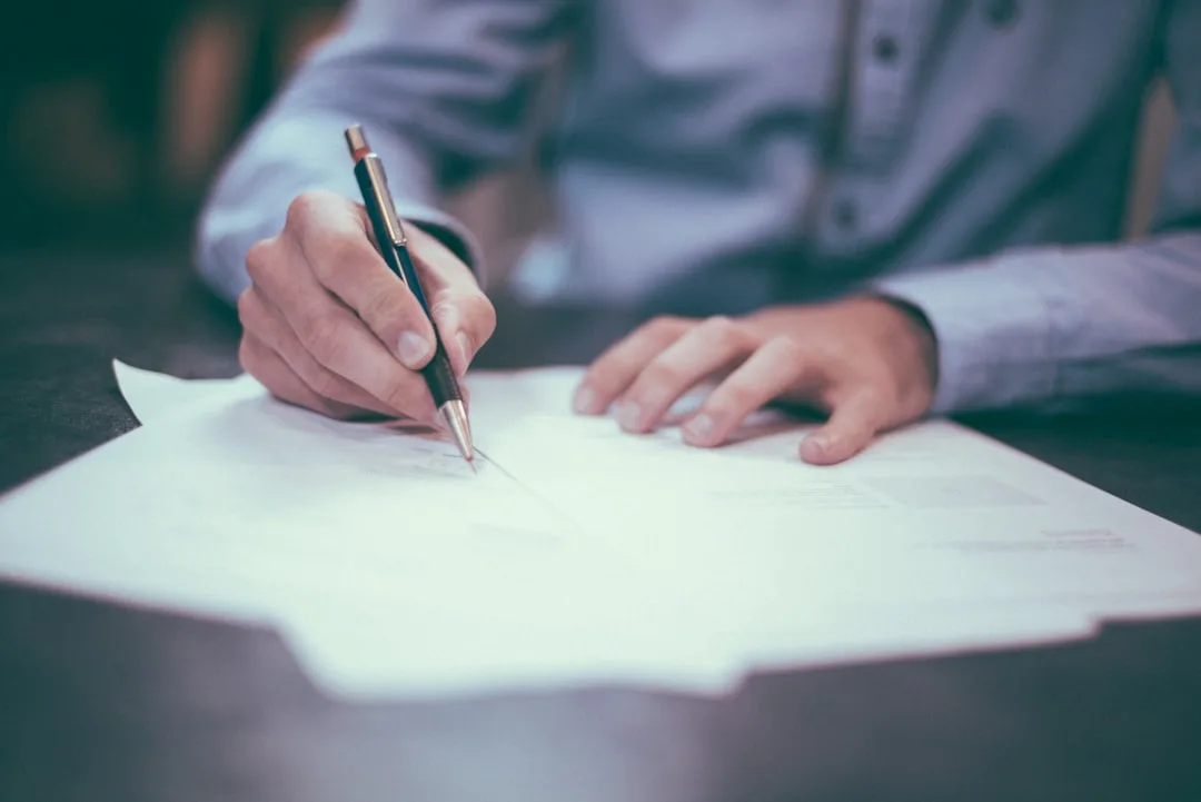 Man signing an insurance contract on paper at a desk — annual travel insurance