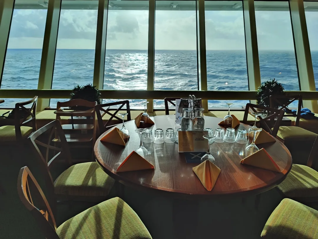 Formally set dining table with wine glasses at the panoramic glass front of a cruise ship with ocean view