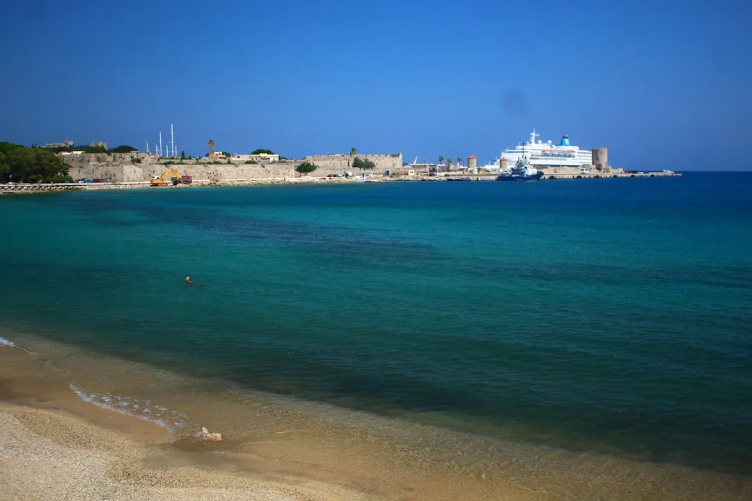 Historic coastal town with ancient city walls and a cruise ship in the blue harbor waters