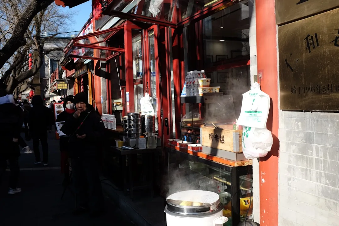 Straßenhändler verkauft dampfende Speisen an einem roten Kiosk in China