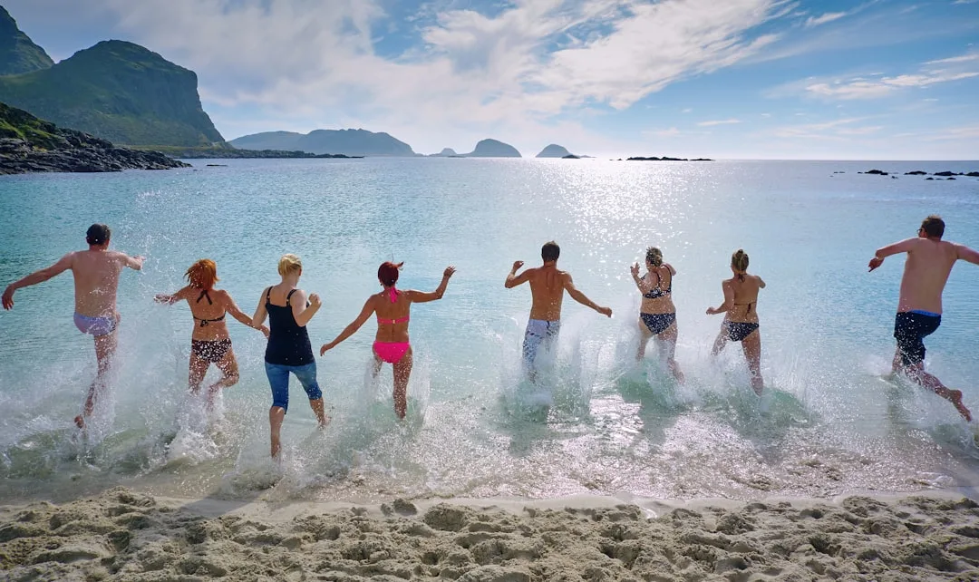 Teenagers jumping together into the sea on a sunny beach
