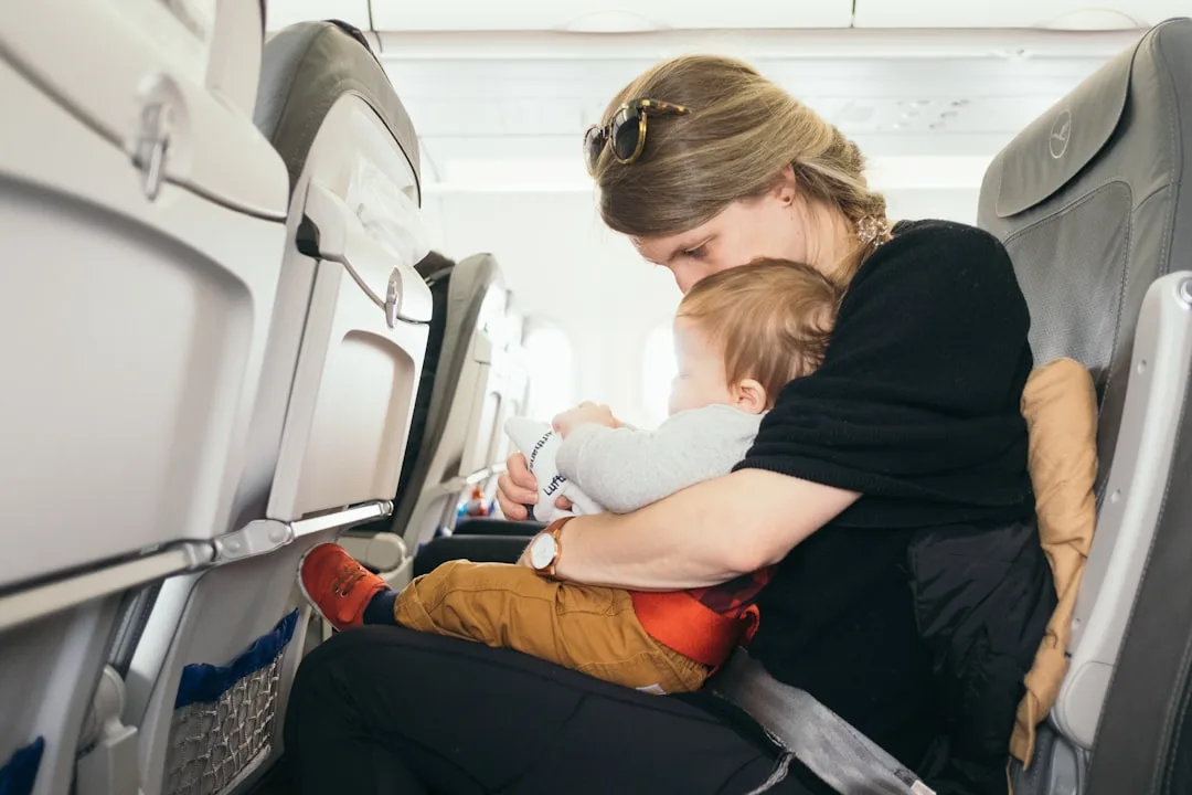 Mutter mit schlafendem Baby auf dem Arm im Flugzeug — erschöpft nach dem Langstreckenflug