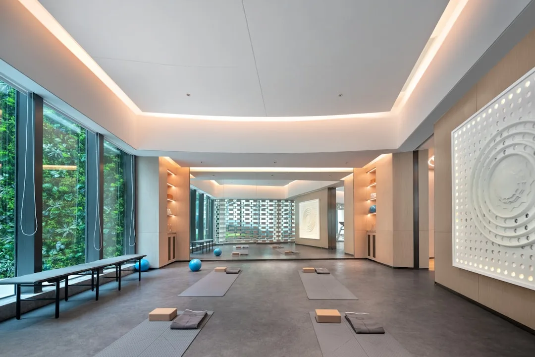 Modernes Yoga-Studio in einem Wellnesshotel mit großen Fensterfronten, Yogamatten auf dem Boden und dekorativer Mandalawand